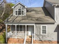 Charming two-story home featuring a covered porch with white railings and gray siding, plus red brick stairs and facade at 1426 Quarter Pt, Raleigh, NC 27615