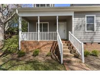 Charming covered front porch with brick accents and white railings, inviting entryway to a cozy home at 1426 Quarter Pt, Raleigh, NC 27615