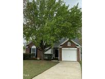 Charming brick home with a well-maintained lawn and a large tree providing shade at 144 Gremar Dr, Holly Springs, NC 27540