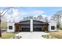 Modern duplex featuring a gray and white exterior, black garage doors, and a concrete driveway and walkway at 1625 Bruce Circle, Raleigh, NC 27604