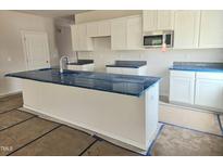 A newly constructed kitchen features white cabinets, an island, and modern stainless-steel appliances at 21 Mildred Pl, Broadway, NC 27505