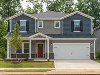 Charming two-story home with a two car garage, red front door and beautifully landscaped front yard at 2202 Cherry Creek Rd, Haw River, NC 27258