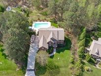 Stunning aerial view of a property with a pool, lush greenery, and charming home exterior at 2909 Timpani Trl, Apex, NC 27539