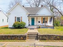 Charming home featuring a quaint front porch and inviting curb appeal with stone retaining wall at 323 W 5Th St, Burlington, NC 27215