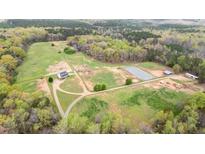 Scenic aerial view of horse property featuring a house, fields, pond, and outbuildings at 3880 L Lawrence Trl, Graham, NC 27253