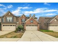 Charming townhome featuring brick and siding exterior, two-car garage, and beautifully landscaped front yard at 520 Brier Crossings Loop, Durham, NC 27703