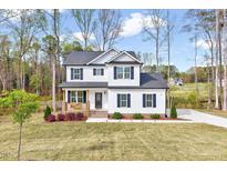 Charming two-story home with a welcoming front porch and beautifully landscaped front yard at 62 Narmada Ct, Zebulon, NC 27597