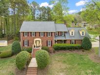 Charming two-story brick home with a well-manicured lawn and lush landscaping creating a welcoming curb appeal at 8000 Old Deer Trl, Raleigh, NC 27615