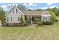 Charming single-story home with a well-manicured lawn and inviting front porch with a red door at 8437 Little Woody Ct, Zebulon, NC 27597