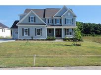 Charming two-story home with light-blue siding, a well-manicured lawn, and a welcoming front porch at 125 Summerlin Dr, Clayton, NC 27527