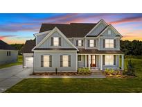 Beautiful two-story home with gray siding, brown shutters, and a well-manicured lawn at twilight at 125 Summerlin Dr, Clayton, NC 27527