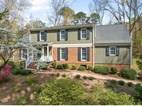 Two-story home featuring a brick and wood facade, complemented by black shutters and a charming landscaped walkway at 1302 Hermitage Rd, Sanford, NC 27330