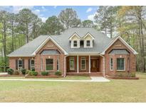 Charming brick home featuring manicured lawn, dormer windows, and covered front porch with classic columns at 15101 Aiken Rd, Wake Forest, NC 27587