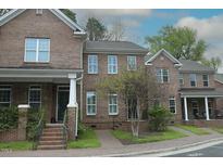Brick townhome featuring a manicured lawn, gray roof, and brick steps leading up to the front door at 1523 Yarborough Park Drive, Raleigh, NC 27604
