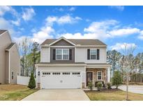 Charming two-story home with gray siding, stone accents, and a two-car garage at 211 Azalea Gaze Dr, Youngsville, NC 27596
