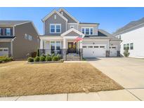 Charming two-story home featuring a welcoming front porch and an attached three car garage at 216 Ocean Jasper Dr, Holly Springs, NC 27540