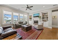 Bright living room featuring a fireplace, built-in shelves, and expansive windows offering scenic views at 216 Ocean Jasper Dr, Holly Springs, NC 27540