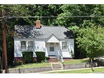 Charming cottage-style home with white siding, brick foundation, and well-maintained landscaping at 301 Dunstan Ave, Durham, NC 27707