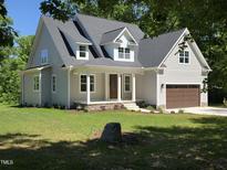 Charming two-story home with a covered front porch, lush green lawn, and attached two-car garage at 5480 Thom Rd, Mebane, NC 27302