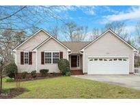 Charming single-story home with neutral siding, red shutters, a well-manicured lawn, and an attached garage at 5604 Stardust Dr, Durham, NC 27712