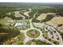 Expansive aerial view of the community, featuring lush greenery, a golf course, roundabout, and recreational facilities at 7 Brandon Pines Ct, Pittsboro, NC 27312