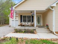 Charming front porch with seating area and an American flag displayed on a beige, single-story home at 104 Black Cloud Dr, Louisburg, NC 27549