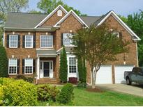 Charming two-story brick home with black shutters, mature landscaping, and a two-car garage at 109 Bright Shade Ct, Holly Springs, NC 27540