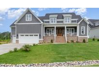 Charming gray two-story home with brick accents, covered porch, and well-manicured lawn at 1221 Azalea Garden Cir, Raleigh, NC 27603