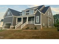 Charming two-story home featuring a welcoming front porch with white columns and a well-maintained lawn at 1221 Azalea Garden Cir, Raleigh, NC 27603