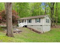 Charming single Gathering home with gray siding and a white stair leading to the front door nestled among lush trees at 1332 Stallings Rd, Chapel Hill, NC 27516
