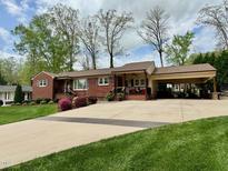 Charming red brick home with a spacious driveway and beautifully landscaped front yard at 1802 Greenbriar Rd, Henderson, NC 27536
