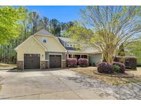 Charming home with a two-car garage, lush landscaping, and an American flag displayed in the front yard at 181 Fawn Hill Ct, Garner, NC 27529
