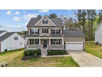 Charming two-story home features a covered front porch, manicured lawn, and a two-car garage at 189 Grey Hawk Dr, Garner, NC 27529