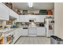 Well-lit kitchen with white cabinets, appliances, and light tile flooring with décor at 2521 Friedland Pl # 201, Raleigh, NC 27617