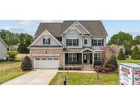 Charming two-story home featuring brick accents, gray siding, and a well-manicured lawn at 265 Beckwith Ave, Clayton, NC 27527