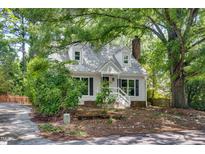 Charming home featuring dormer windows, white siding, mature trees, and a cozy front porch at 3421 E Jameson Rd, Raleigh, NC 27604