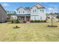 Charming two-story home features a symmetrical facade, gray siding, and a well-manicured lawn at 401 Club Center Dr, Youngsville, NC 27596