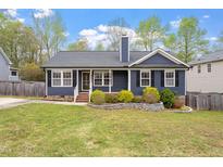 Charming blue home with a well-manicured lawn and inviting front yard landscaping at 408 Teal Lake Dr, Holly Springs, NC 27540