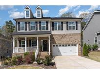 Charming two-story home features a brick and siding exterior, dormer windows, and a welcoming front porch at 420 Cahors Trl, Holly Springs, NC 27540