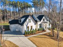 Beautiful white home with a three-car garage and well-manicured landscaping on a sunny day at 472 Stonecrest Way, Pittsboro, NC 27312