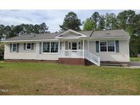 Charming one-story home with a well-manicured lawn and inviting front porch and blue shutters at 1033 Silas Moore Rd, Benson, NC 27504