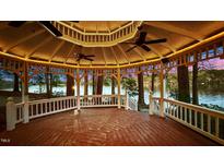 Lakefront gazebo with wooden floors, lighting, and ceiling fans providing a perfect outdoor gathering space at 104 Stage Line Cv, Louisburg, NC 27549