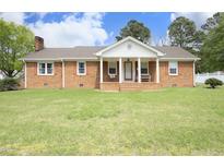 Charming brick ranch home with a front porch, swing, and well-manicured lawn at 1104 W Cole St, Dunn, NC 28334