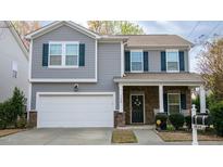 Charming two-story home featuring a garage, stone accents and a covered front porch with rocking chairs at 1620 Frog Hollow Way, Wake Forest, NC 27587