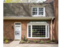 Charming brick home featuring a bay window and a white front door with beautiful landscaping at 2 Banbury Ln # 2, Chapel Hill, NC 27517