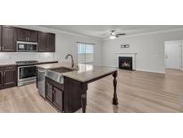 Well-equipped kitchen with island, stainless appliances, granite counters, and open view to the living room fireplace at 233 Stone River Dr, Wendell, NC 27591