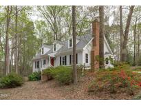 Charming two-story home with white siding, black shutters, red door, and mature landscaping at 2629 Sweetgum Dr, Apex, NC 27539