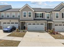 Charming townhome featuring a two-car garage, grey siding, and beautifully manicured landscaping at 486 Autumn Rain St, Cary, NC 27519