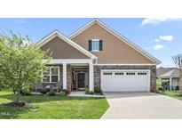Charming home featuring a two-car garage, stone accents, covered entryway, and manicured lawn at 667 Ashley Woods Dr, Gibsonville, NC 27249