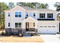 Charming two-story home with stone accents, attached garage, and landscaped front yard at 68 Tee Time Ter, Benson, NC 27504